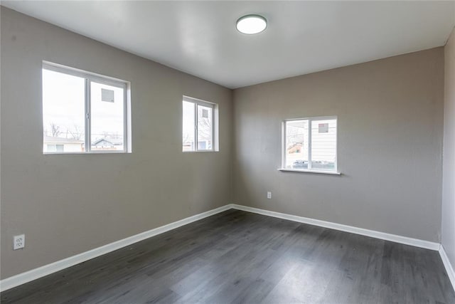 unfurnished room with baseboards and dark wood finished floors