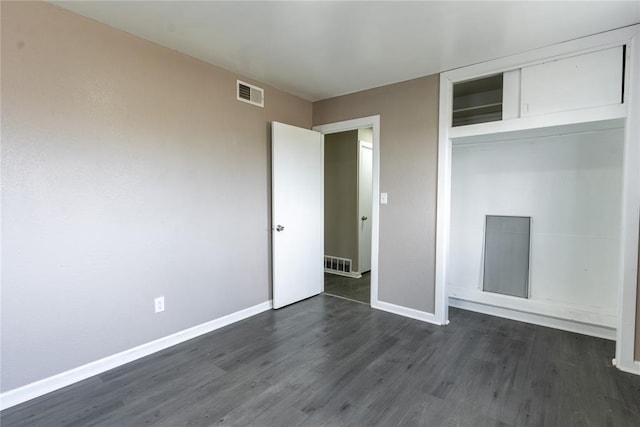 unfurnished bedroom with visible vents, dark wood-style flooring, baseboards, and a closet