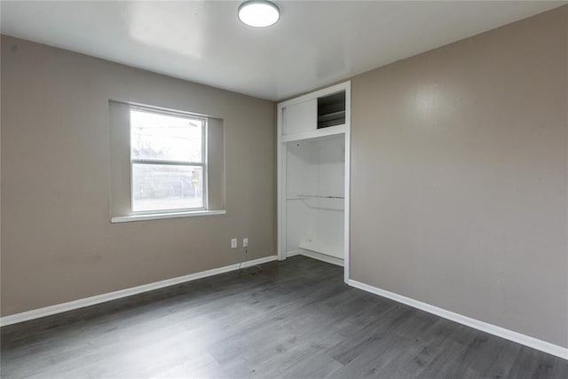 unfurnished bedroom featuring dark wood-type flooring, baseboards, and a closet