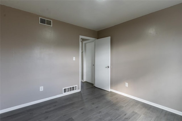 unfurnished room with baseboards, visible vents, and dark wood finished floors