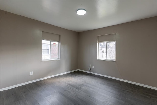 spare room featuring plenty of natural light, baseboards, and dark wood-style floors
