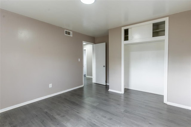 unfurnished bedroom featuring baseboards, dark wood-type flooring, and visible vents