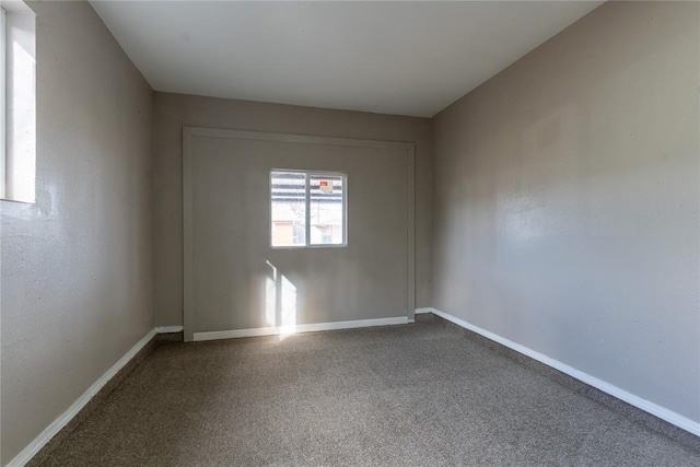 empty room featuring baseboards and carpet flooring