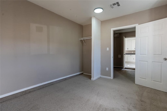 unfurnished bedroom with carpet flooring, baseboards, vaulted ceiling, visible vents, and a closet