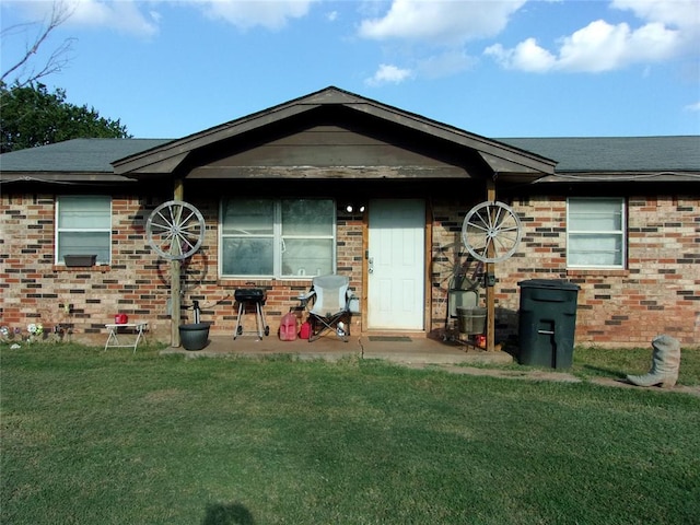 rear view of house featuring a lawn, brick siding, and a patio