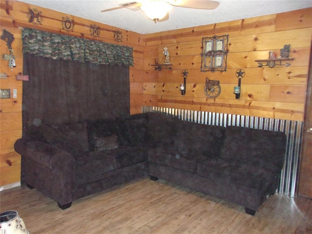 living room with wood walls, ceiling fan, and wood finished floors