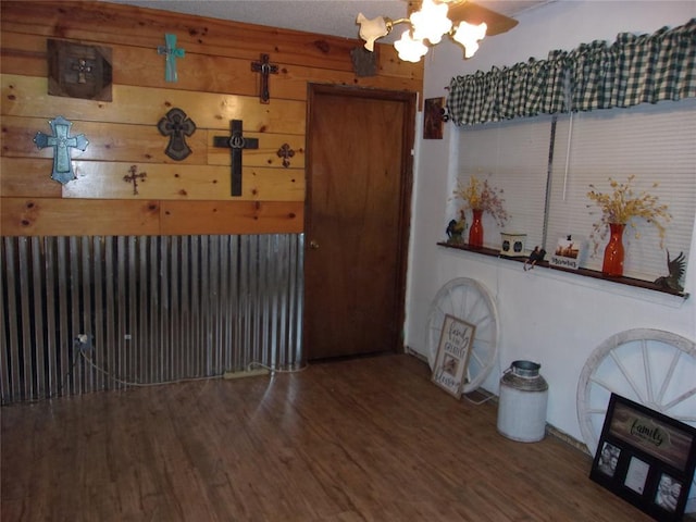 dining area featuring wooden walls, a notable chandelier, and wood finished floors