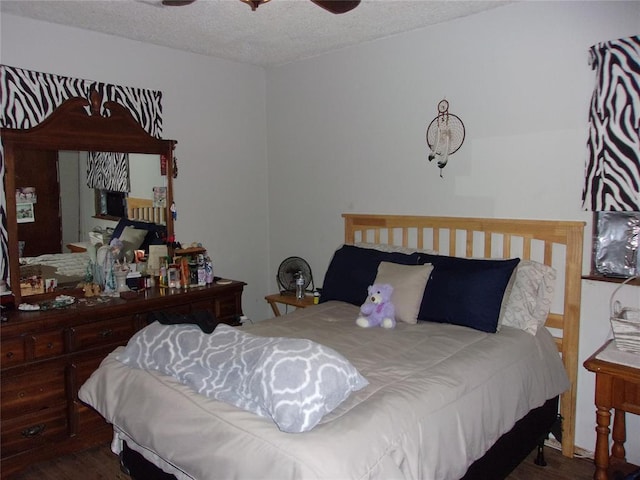 bedroom with a ceiling fan, a textured ceiling, and wood finished floors