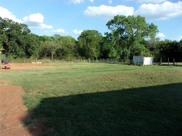 view of yard featuring an outdoor structure, fence, and a shed