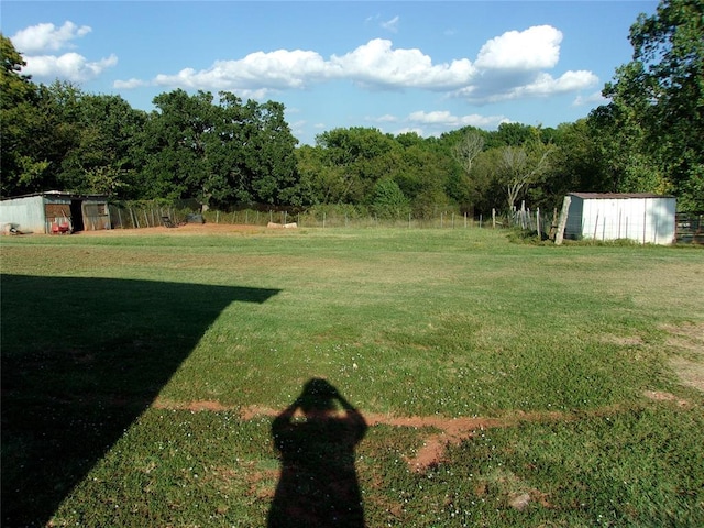 view of yard featuring an outdoor structure, fence, and a storage shed