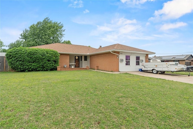 single story home featuring concrete driveway, brick siding, fence, and a front lawn