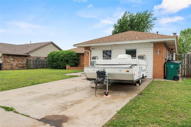 view of front of home with brick siding, a front lawn, roof with shingles, and fence