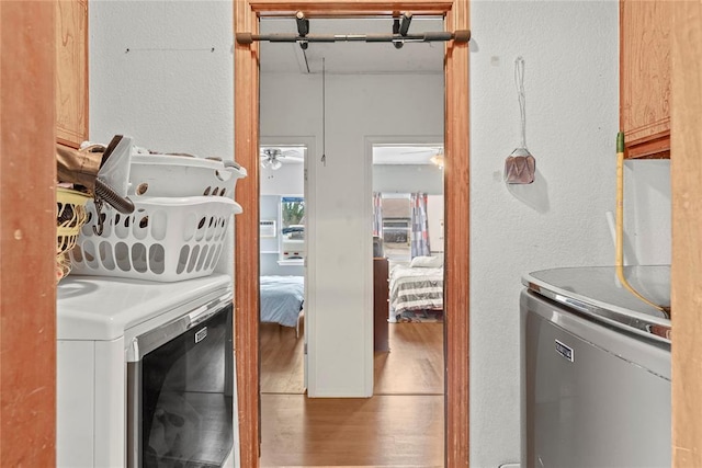 washroom featuring water heater, separate washer and dryer, cabinet space, and wood finished floors