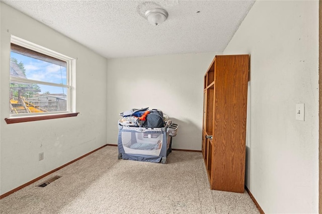 bedroom with a textured ceiling, visible vents, baseboards, and carpet
