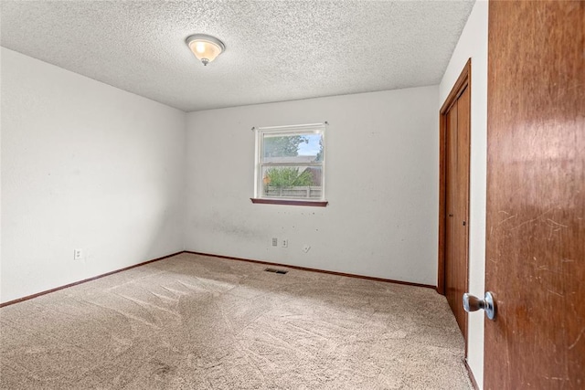 unfurnished bedroom with baseboards, carpet flooring, a textured ceiling, and visible vents
