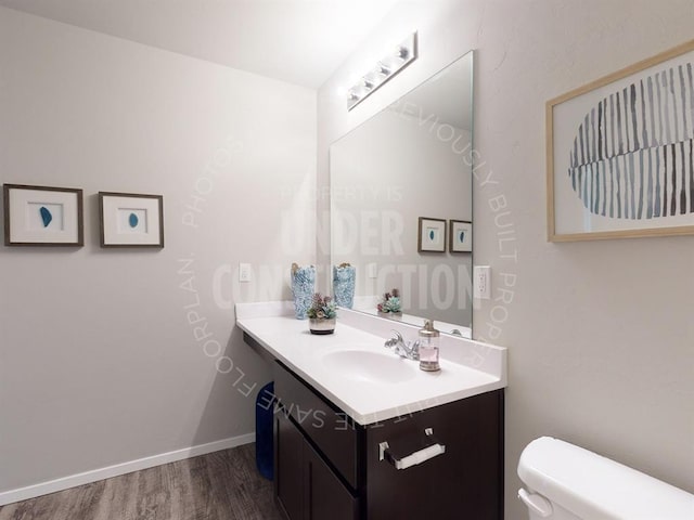 half bath with vanity, toilet, and wood finished floors