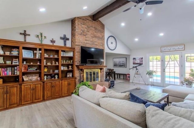 living area with beam ceiling, a fireplace, light wood-style floors, high vaulted ceiling, and a ceiling fan