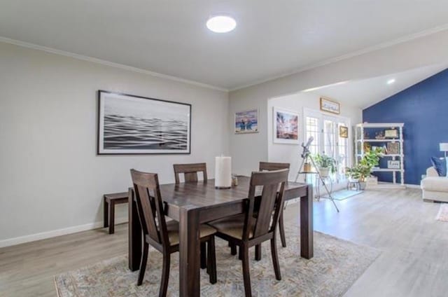 dining room with crown molding, baseboards, and light wood-style floors