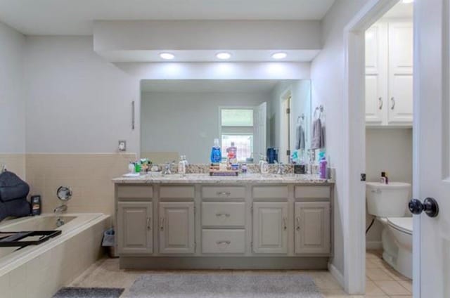 full bathroom featuring a sink, tile patterned flooring, double vanity, toilet, and a garden tub