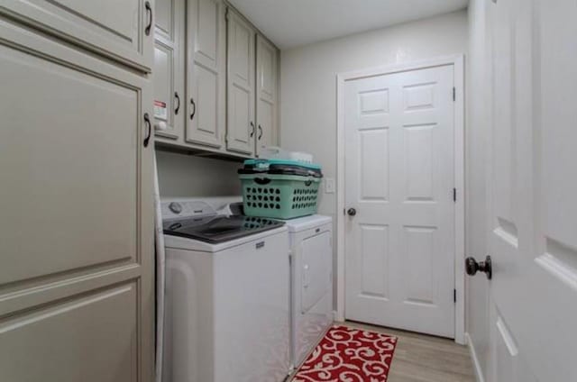 laundry room with light wood-type flooring, cabinet space, and washing machine and dryer