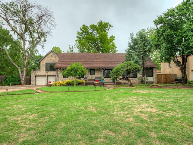 view of front of property featuring fence, stone siding, a garage, a front yard, and concrete driveway