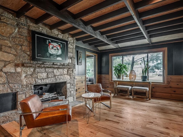 sitting room with wooden walls, a fireplace, a wainscoted wall, wood finished floors, and beamed ceiling