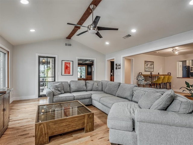 living area with lofted ceiling with beams, light wood-style flooring, and visible vents