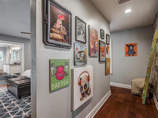 hallway featuring an inviting chandelier, visible vents, wood finished floors, baseboards, and recessed lighting
