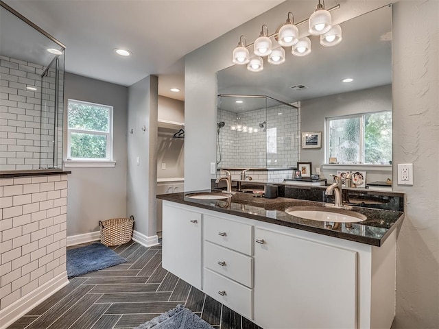 full bathroom featuring double vanity, baseboards, a sink, and a stall shower