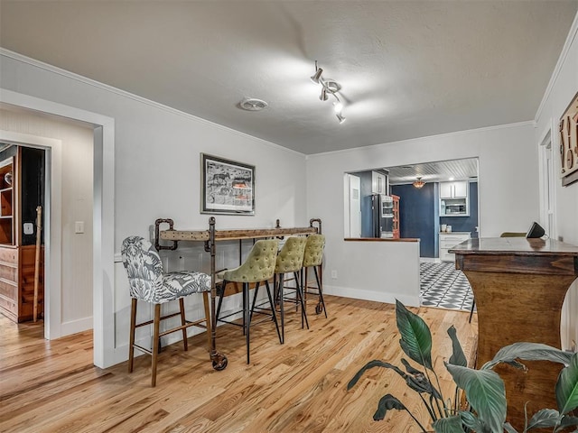 dining area with crown molding, light wood finished floors, and baseboards
