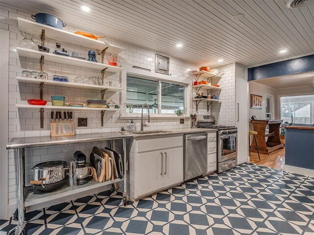 kitchen with open shelves, a sink, light floors, stainless steel appliances, and white cabinetry