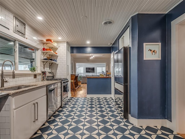 kitchen featuring white cabinets, a sink, stainless steel appliances, light floors, and visible vents