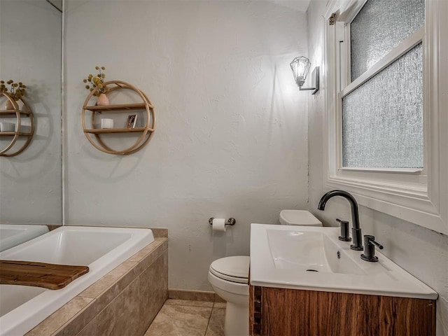 bathroom with tile patterned flooring, vanity, toilet, baseboards, and tiled tub