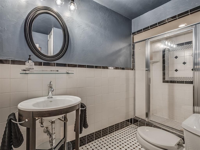 full bathroom with tile walls, a textured wall, a stall shower, and toilet
