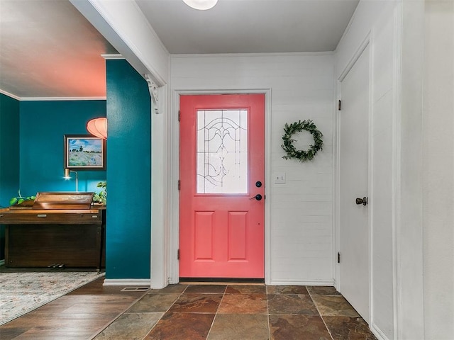 entryway featuring baseboards, ornamental molding, and stone finish floor