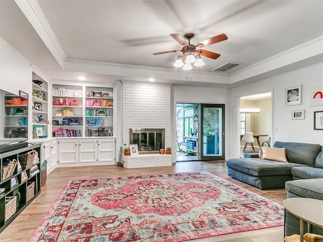 living room with crown molding, ceiling fan, a tray ceiling, and visible vents