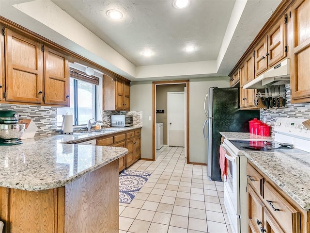 kitchen with electric range, a sink, a peninsula, light tile patterned floors, and under cabinet range hood