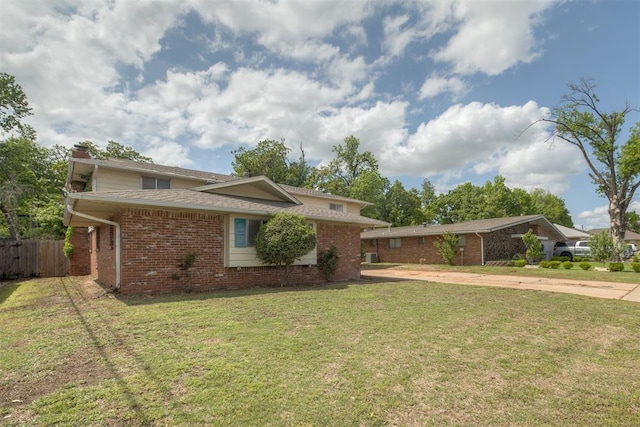 view of front of home featuring fence, a chimney, a front lawn, and brick siding