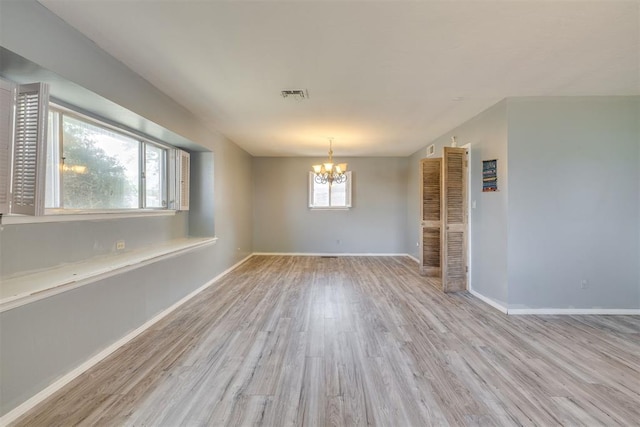 unfurnished dining area featuring visible vents, baseboards, wood finished floors, and a chandelier