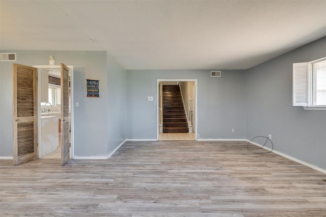 empty room with visible vents, stairs, baseboards, and wood finished floors