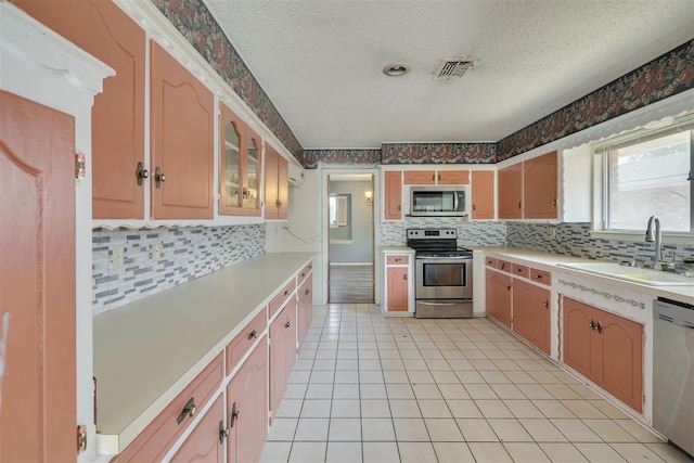 kitchen with visible vents, decorative backsplash, light countertops, a sink, and appliances with stainless steel finishes