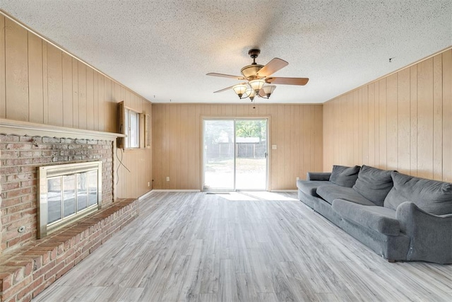 living area featuring a textured ceiling, ceiling fan, wood walls, and wood finished floors