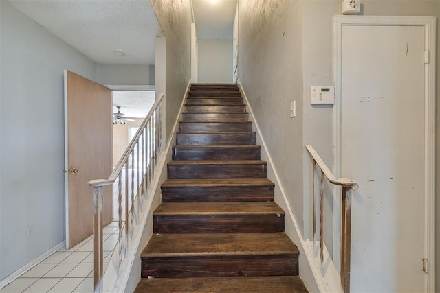 staircase with baseboards, a ceiling fan, and tile patterned flooring