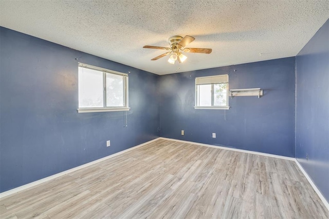 unfurnished room featuring baseboards, a ceiling fan, a textured ceiling, and wood finished floors