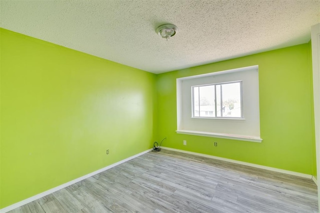 spare room with baseboards, a textured ceiling, and wood finished floors