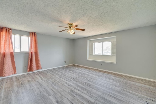 empty room with a textured ceiling, ceiling fan, a healthy amount of sunlight, and wood finished floors
