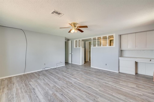 unfurnished living room with baseboards, a ceiling fan, light wood finished floors, and a textured ceiling