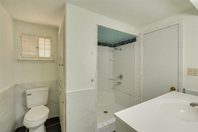 bathroom featuring a sink, a textured ceiling, a stall shower, and toilet