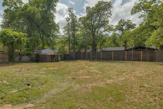 view of yard with a fenced backyard, an outbuilding, and a shed