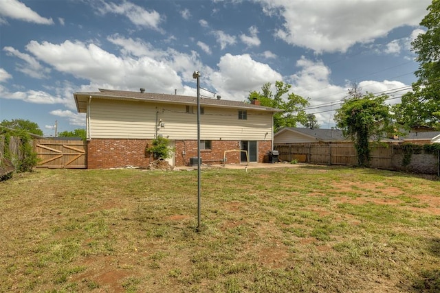 back of house with a patio, brick siding, a fenced backyard, and a lawn
